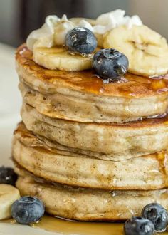 a stack of pancakes topped with bananas and blueberries