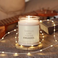 a candle that says smells like you're engaged on it next to a guitar