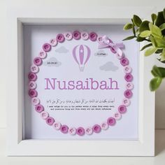 a frame with buttons and a pink ribbon around it that says, nusaibah