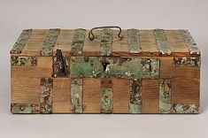 an old wooden box with green paint on the lid and handles, sitting on a white surface