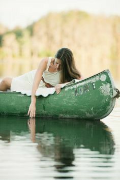 a woman laying on top of a green boat