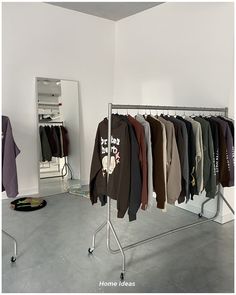 clothes are hanging on a rack in front of a mirror and other clothing is hung up