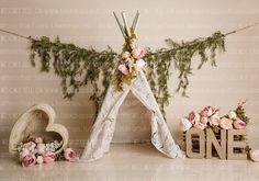 a teepee tent with flowers and greenery on the wall next to it is one sign