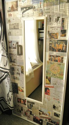 a mirror that is sitting on the ground in front of a wall covered with newspaper