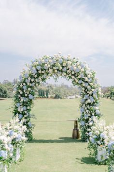 an outdoor ceremony with white flowers and greenery on the grass, in front of a golf course