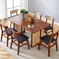 a dining table with four chairs and a bowl of fruit on top of the table