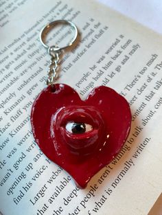 a red heart shaped keychain on top of an open book with eyeballs in it