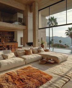 a living room filled with furniture next to a large window overlooking the water and palm trees