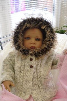 a baby doll is dressed in a furry coat