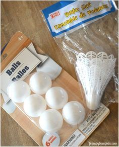 some white plastic balls are sitting on a wooden table next to a package of golf tees