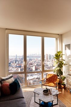 a living room filled with furniture and a large window covered in lots of windows overlooking the city