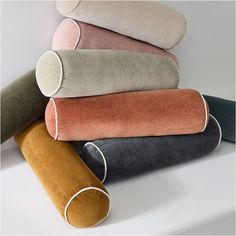 four different colored pillows stacked on top of each other with one rolled up in the middle