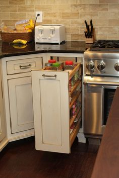 an open cabinet in the middle of a kitchen with stainless steel appliances and wood flooring