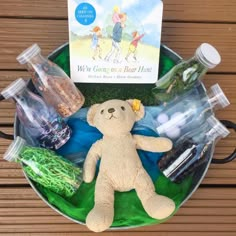 a teddy bear sitting on top of a green tray filled with bottles and other items