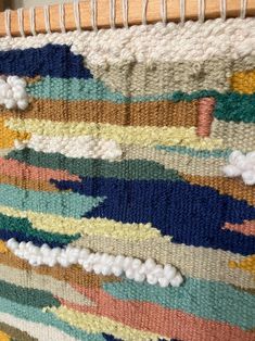 a close up view of a multicolored rug on a wooden frame with yarn