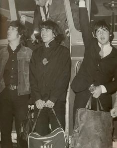 black and white photograph of the rolling stones on a bus with their hand in the air