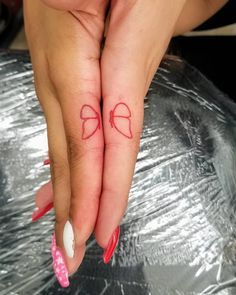 two hands with red bows on them and one has a small bow tattoo on the middle finger