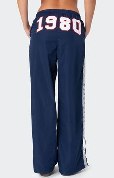 These Edikted 1980 Nylon Track Pants offer both style and comfort, making them perfect for a sporty yet fashionable look. They're ideal for any activity, ensuring you feel comfortable and confident throughout your entire day. Track pantsLace stripe detailingSlitted hemAdjustable waist tieEmbroidered graphic textPolyesterModel wears size SModel height is 5'8Item care: Machine wash at maximum 30C, wash with similar colors, do not bleach, do not tumble dry, iron at a maximum of 110C, do not dry clean. Edikted Womens 1980 Nylon Track Pants - Blue size XL Sweatpants With Words On Back, Sporty Fits, Cool Sweatpants, White Track Pants, Nylon Track Pants, Vintage Sweatpants, Graphic Sweatpants, Hip Hop Pants, Birthday Fits