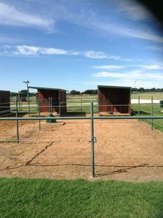 a fenced in area with several stalls on each side and grass around the perimeter