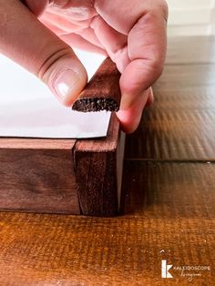 a person is holding a piece of wood with their fingers on the edge of it