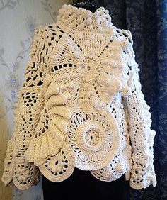 a white crocheted jacket is hanging on a mannequin