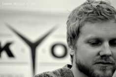 a man with blonde hair and beard is looking at the camera while holding his hand to his face