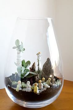 a glass vase filled with plants on top of a wooden table