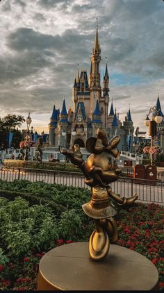 a gold mickey mouse statue in front of a castle