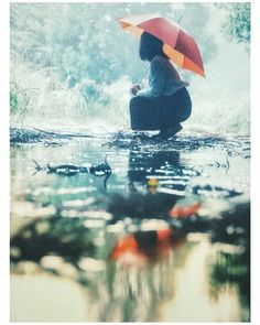 a person sitting in the water with an umbrella