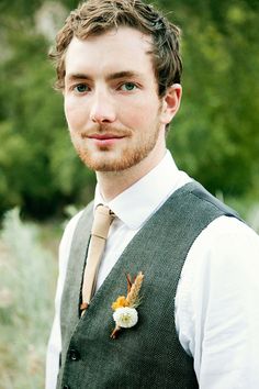 a man wearing a vest and tie with a flower in his lapel