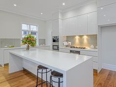 a large white kitchen with an island in the middle