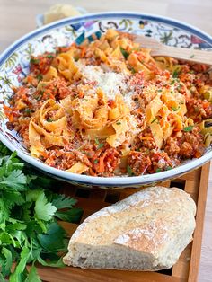 a bowl of pasta and bread on a cutting board