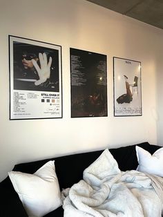 a black couch with white pillows and pictures on the wall