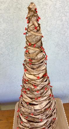 a christmas tree made out of driftwood with red berries on the top and bottom