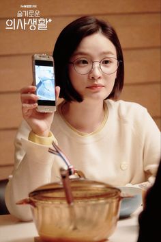 a woman sitting at a table holding up a cell phone