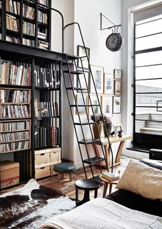 a living room filled with lots of furniture and bookshelves next to a window