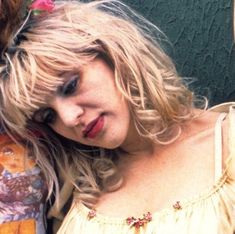 a woman with blonde hair standing next to a man in a yellow shirt and flowered headband