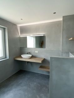 a bathroom with a sink, mirror and shelves on the wall next to a window