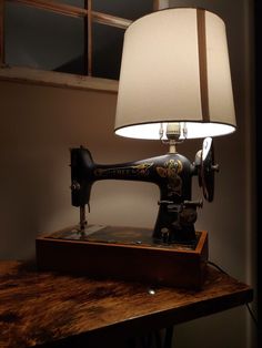 an old fashioned sewing machine sitting on top of a wooden table next to a lamp