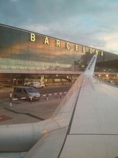 an airplane wing with the word barcelona on it's side and cars parked in front