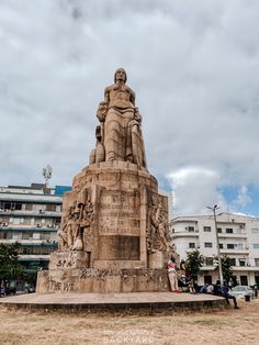 there is a large statue in the middle of this field with people sitting around it