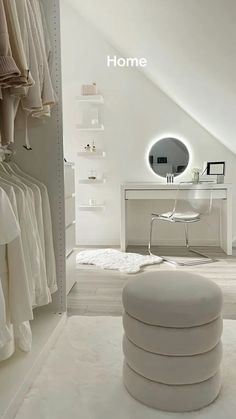 a room with white furniture and clothes hanging on the walls, along with a round mirror