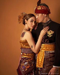 a man and woman dressed in traditional thai garb posing for a photo with their arms around each other