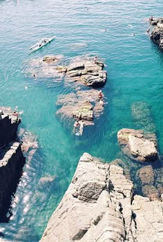 people are swimming in the water near some rocks