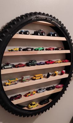 a wall mounted toy car display in the shape of a tire with shelves filled with cars