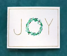 a card with the word joy painted on it and a wreath in the middle that says joy