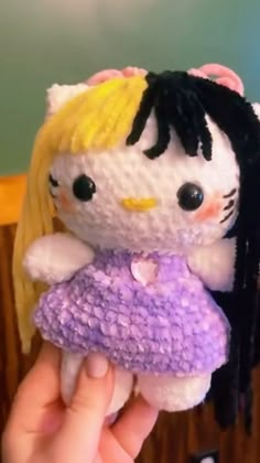 a hello kitty doll holding onto a stuffed animal with long hair and wearing a purple dress