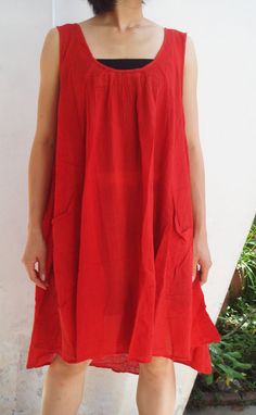 a woman standing in front of a white wall wearing a red dress and black shoes