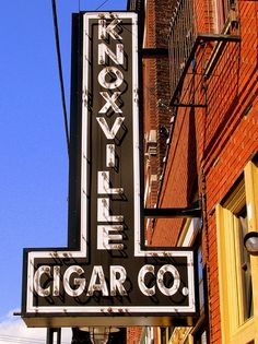 an old neon sign on the side of a building in front of a brick building