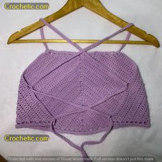 a crocheted top is hanging on a wooden hanger and it has an open back